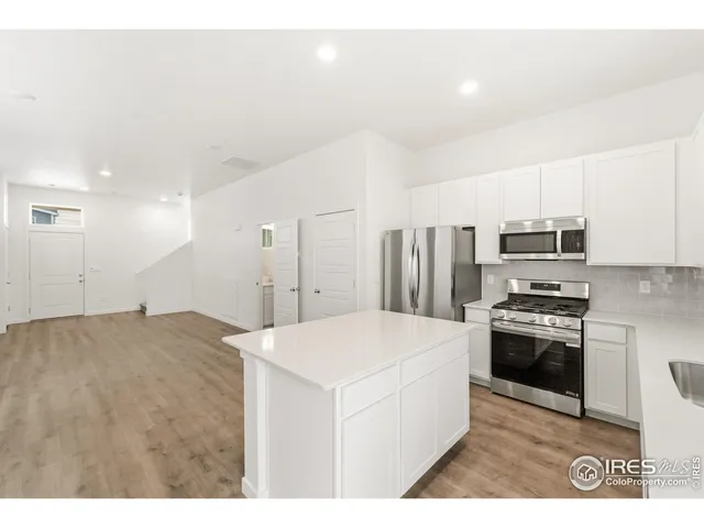 a kitchen with stainless steel appliances kitchen island sink stove and white cabinets