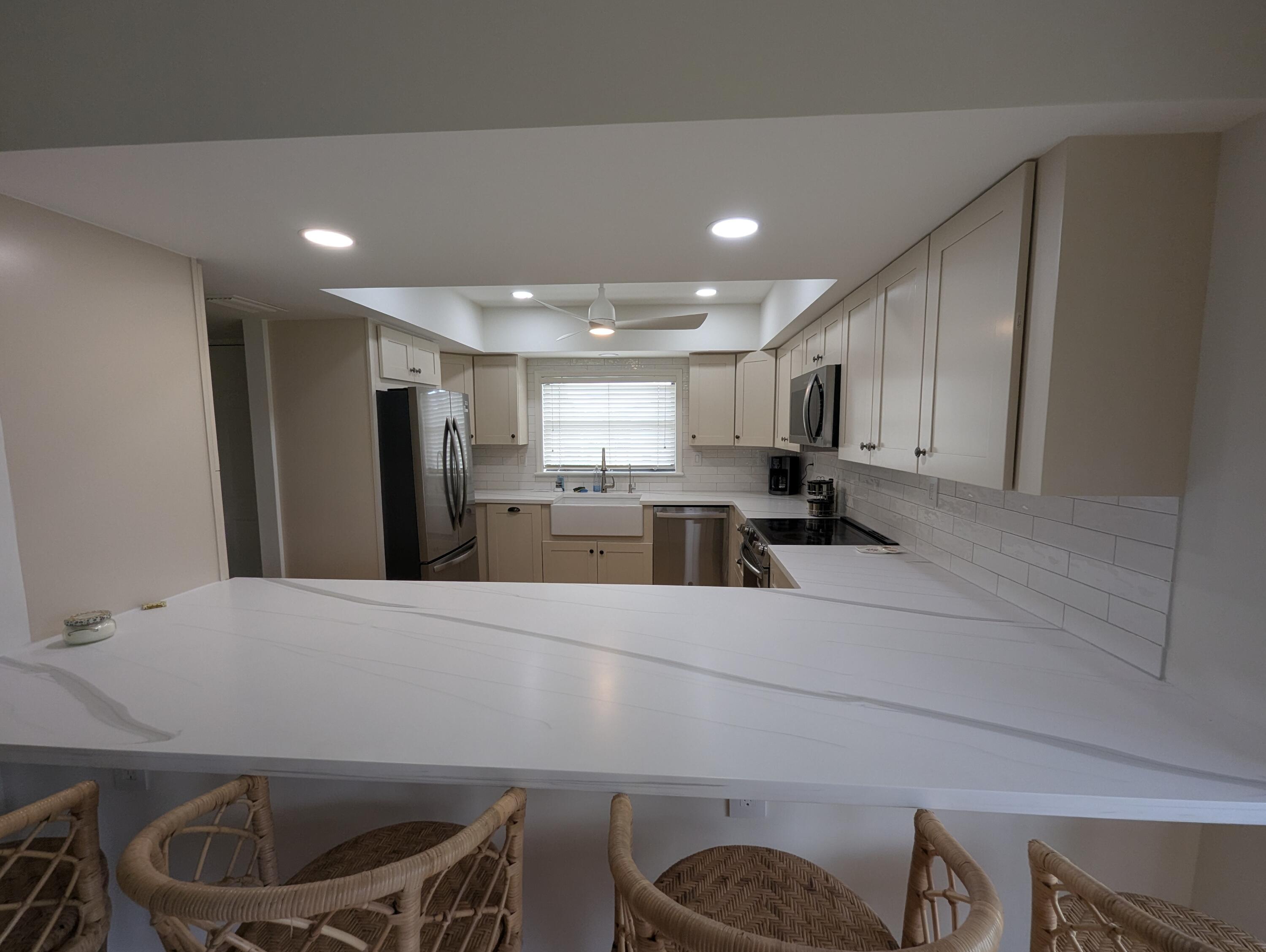 404 Clubhouse Circle Jupiter, FL 33477 - Photo 6 of 20 a kitchen with stainless steel appliances granite countertop a sink a stove a refrigerator cabinets and a dining table