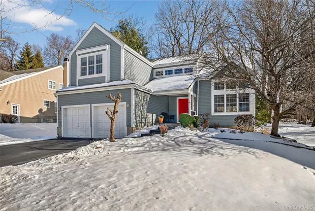 a front view of a house with a yard and large tree