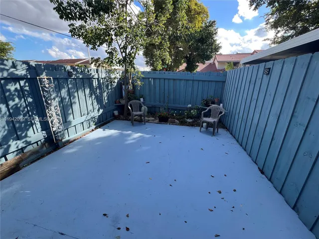 a view of backyard with a table and chairs and wooden fence