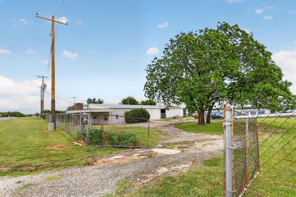 1092 West Highway 199 Springtown, TX 76082 - Photo 2 of 29 Chain-link fencing with gate encompasses the property, featuring a gravel driveway