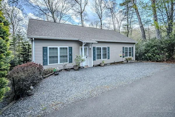 a view of a house with a yard and large tree