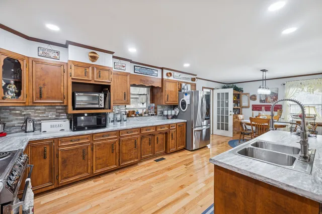 a kitchen with stainless steel appliances a refrigerator a sink dishwasher a stove and white cabinets with wooden floor
