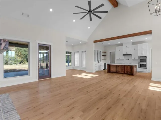 a view of a big room with wooden floor and a kitchen