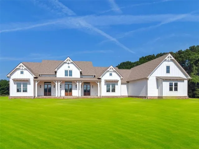 a view of a house next to a big yard and large trees