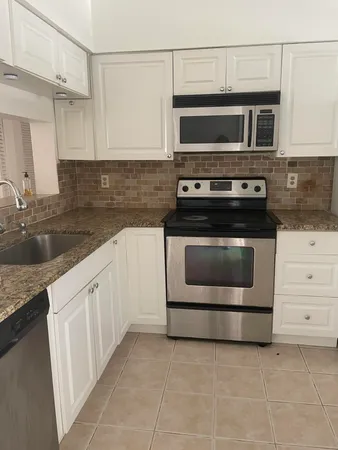 a kitchen with granite countertop a stove microwave and sink