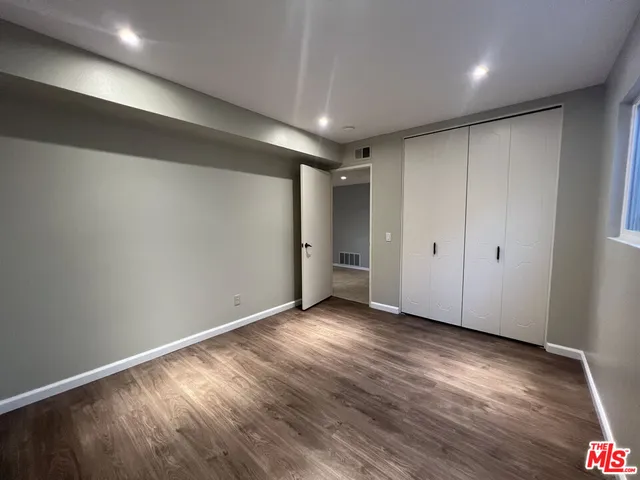 an empty room with wooden floor & closet area
