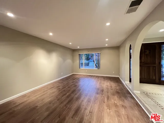 an empty room with wooden floor and a ceiling fan
