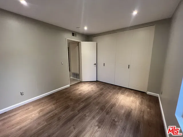 an empty room with wooden floor and entrance