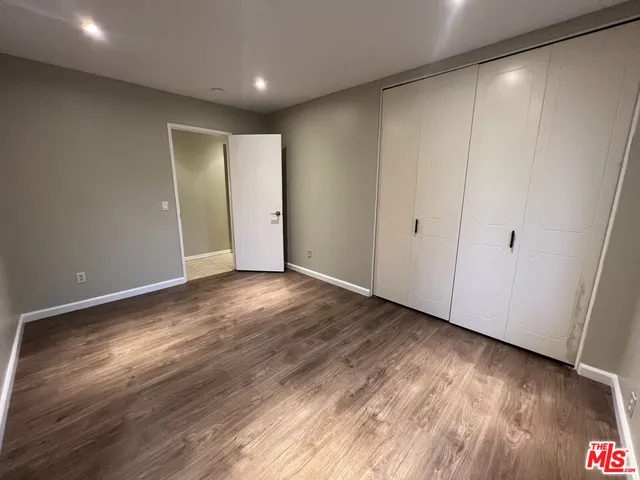 a view of an empty room with wooden floor and closet area