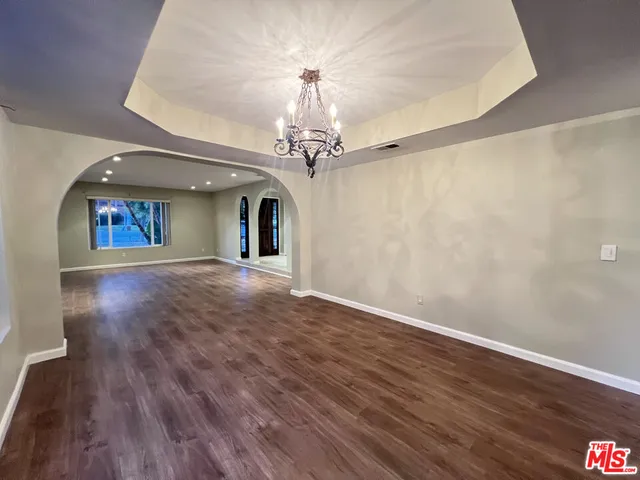 a view of a hallway with wooden floor and chandelier