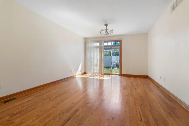 an empty room with wooden floor and window