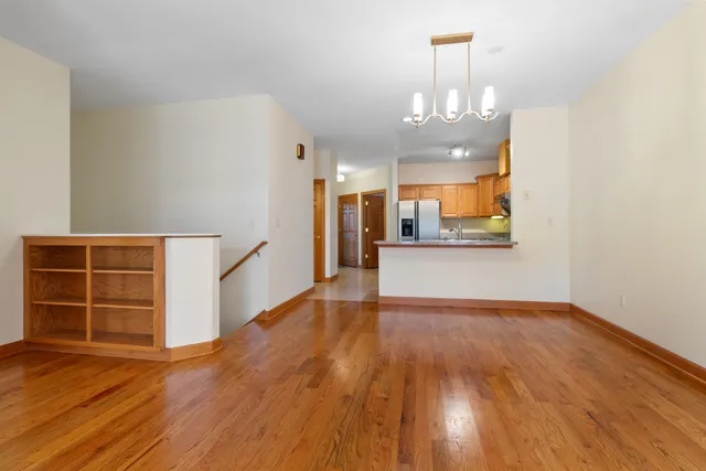an empty room with wooden floor and kitchen view