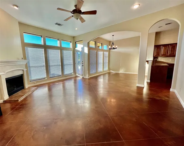 a view of a livingroom with wooden floor a ceiling fan and windows