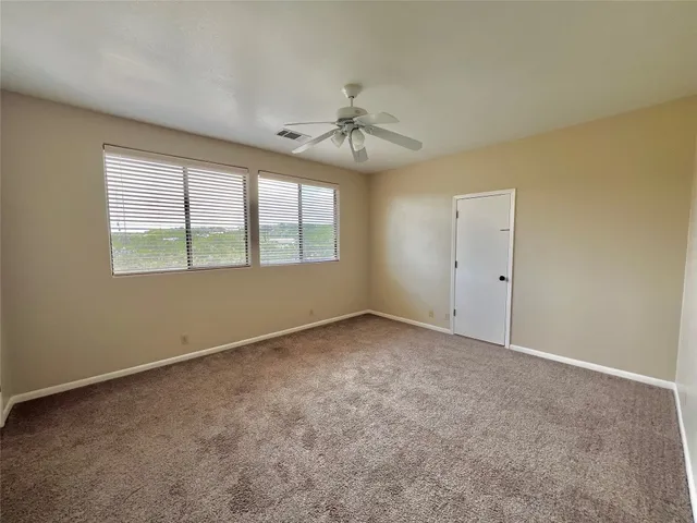 an empty room with a window and ceiling fan