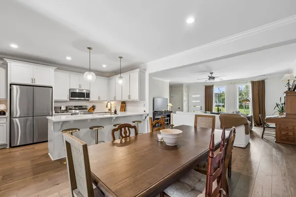 a dining room with stainless steel appliances a dining table chairs and wooden floor