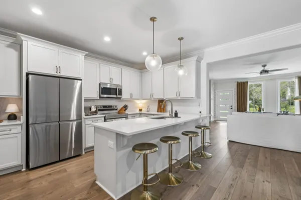 a kitchen with stainless steel appliances granite countertop a refrigerator a stove a sink dishwasher a refrigerator and white cabinets with wooden floor