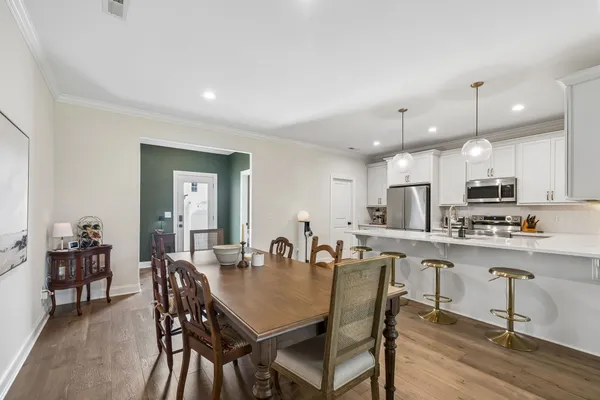 a view of a dining room and livingroom with furniture wooden floor a rug a painting and a chandelier
