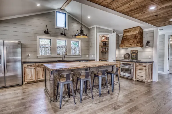 a kitchen with stainless steel appliances granite countertop a table chairs a sink and a refrigerator