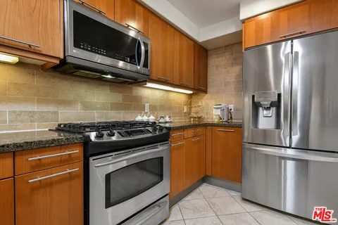 a kitchen with stainless steel appliances granite countertop a stove microwave and refrigerator