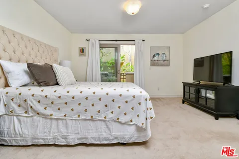 a living room with a bed furniture flat screen tv and a large window