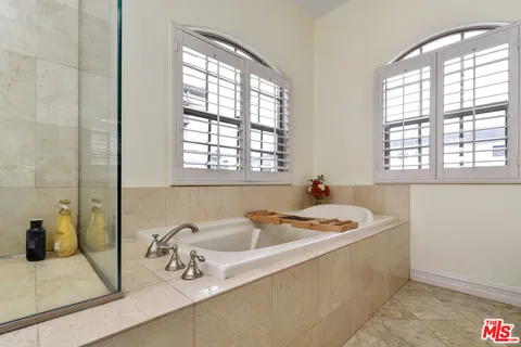 a bathroom with a tub sink mirror and shower