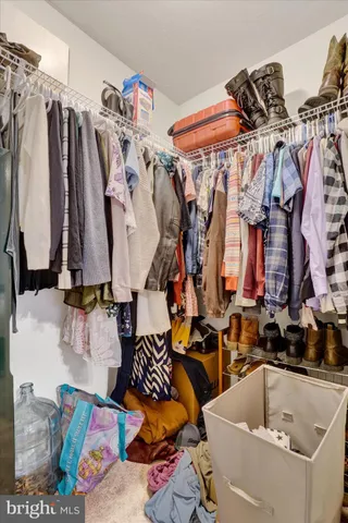 a view of walk in closet with clothes and shoes