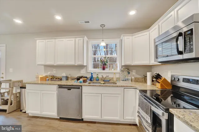 a kitchen with stainless steel appliances granite countertop a sink stove and cabinets