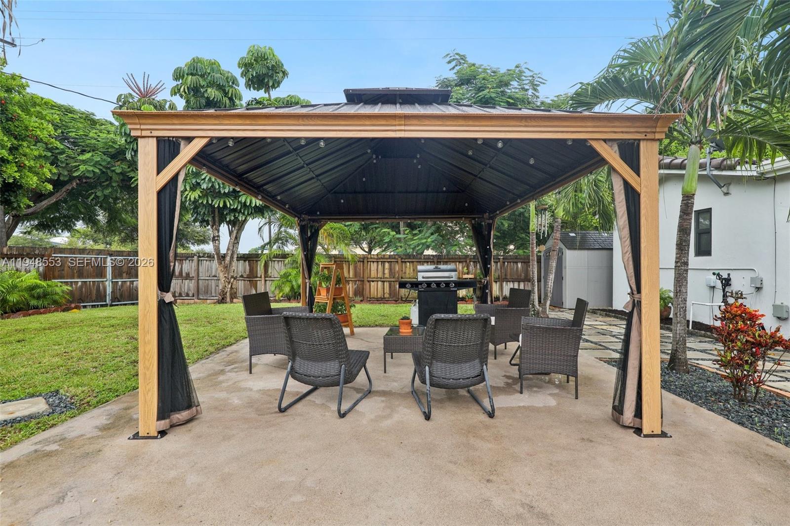 5301 Pierce Street Hollywood, FL 33021 - Photo 40 of 45 a view of patio with a table and chairs under an umbrella with a small yard