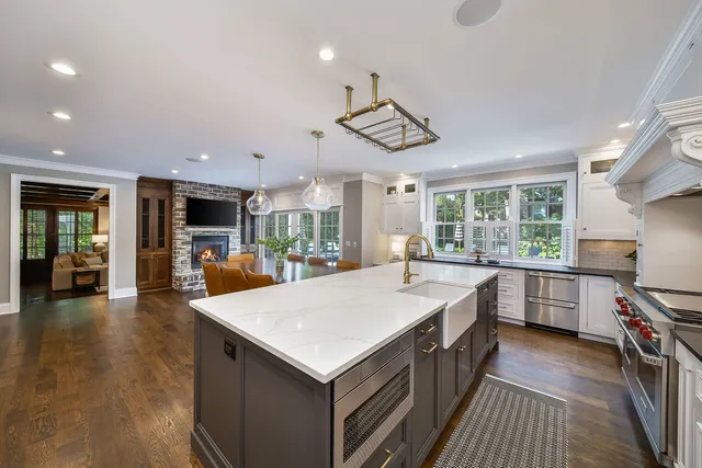 a open kitchen with stainless steel appliances granite countertop a stove top oven a sink a dining table and chairs with wooden floor