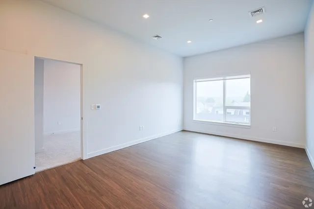an empty room with wooden floor and window