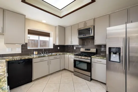 a kitchen with stainless steel appliances granite countertop a stove a sink and a refrigerator