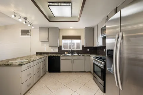 a kitchen with stainless steel appliances granite countertop a stove a sink and a refrigerator