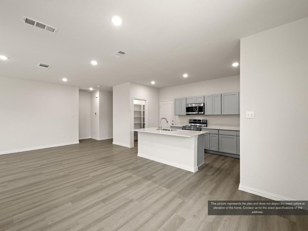 1805 Zelvia Lane Waco, TX 76708 - Photo 6 of 22 a view of kitchen with kitchen island granite countertop a stove top oven a sink and white cabinets with wooden floor