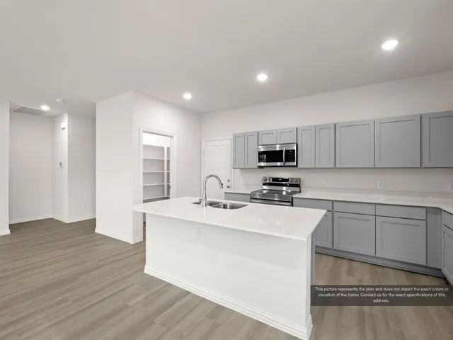 a view of kitchen with kitchen island granite countertop a stove top oven a sink and white cabinets with wooden floor
