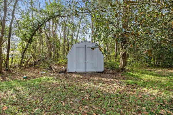 a backyard of a house with a large tree and wooden fence