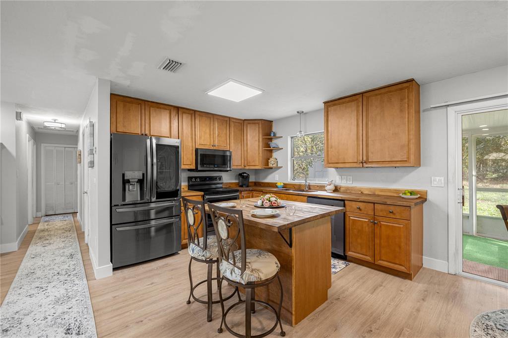 16675 Southwest 143rd Avenue Archer, FL 32618 - Photo 5 of 26 a kitchen with a refrigerator a stove top oven a sink dishwasher and wooden cabinets with wooden floor