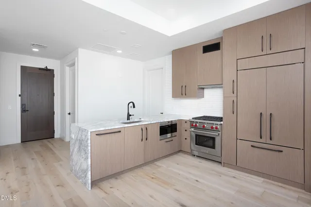 a kitchen with stainless steel appliances granite countertop a refrigerator a sink and white cabinets