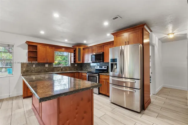 a kitchen with stainless steel appliances granite countertop a refrigerator a stove and a sink