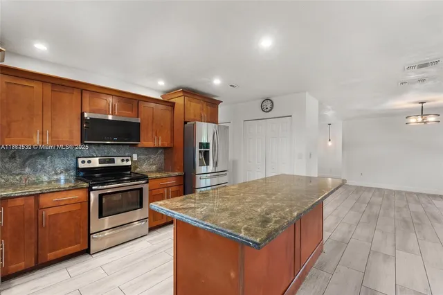 a kitchen with stainless steel appliances granite countertop refrigerator sink and wooden cabinets