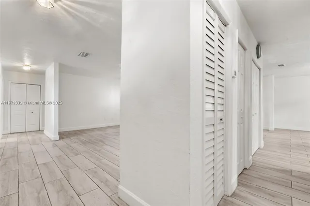 a kitchen with stainless steel appliances kitchen island granite countertop a stove a refrigerator a sink a microwave oven with white cabinets and wooden floor