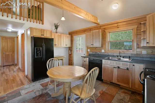 a kitchen with stainless steel appliances granite countertop a sink a stove a refrigerator a dining table and chairs