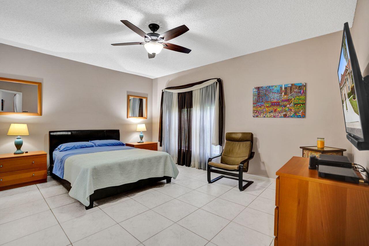 6251 Long Key Lane Boynton Beach, FL 33472 - Photo 13 of 41 a bedroom with a bed and a chandelier