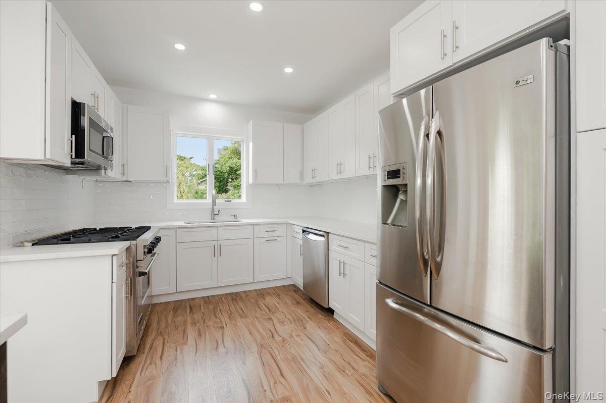 56 Oak Beach Road Babylon, NY 11702 - Photo 13 of 30 Newly remodeled kitchen shines with a oversized center island with quartz countertops and stainless steel appliances.