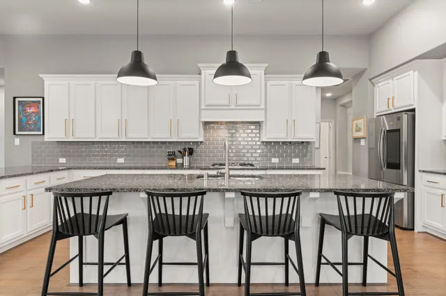 a kitchen with stainless steel appliances granite countertop a stove a sink and a refrigerator with wooden floor