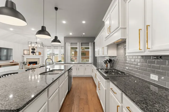a kitchen with granite countertop a sink a counter space appliances and cabinets