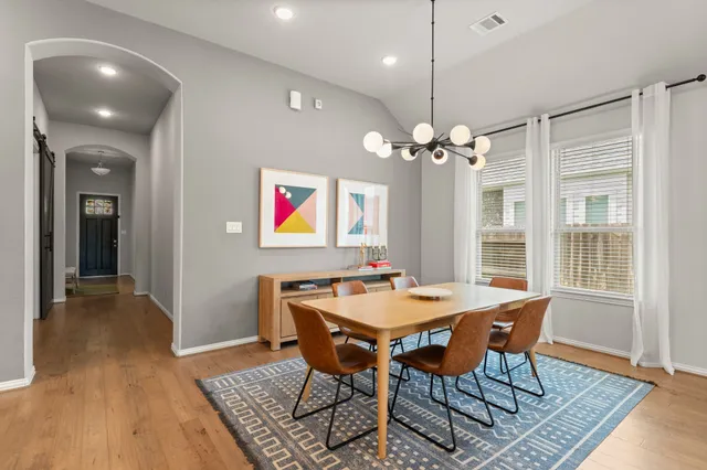 a dining room with wooden floor a chandelier a wooden table and chairs