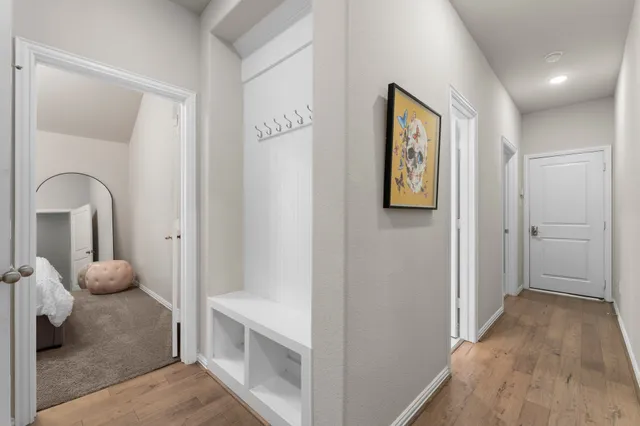 a view of a hallway to a livingroom with wooden floor and furniture