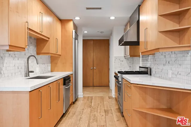 a kitchen with stainless steel appliances granite countertop a sink a stove and a refrigerator