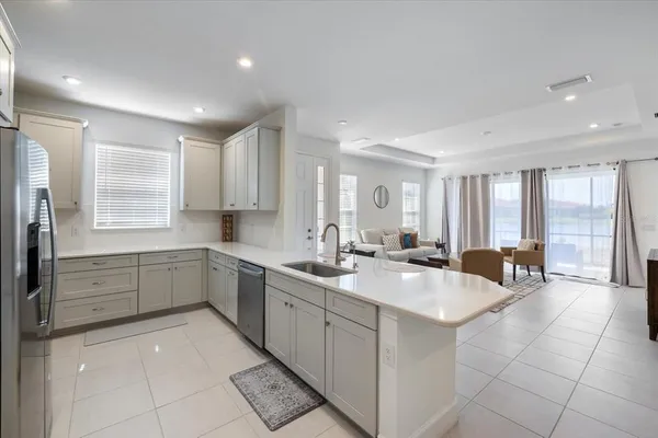 a large white kitchen with a sink large mirror and cabinets